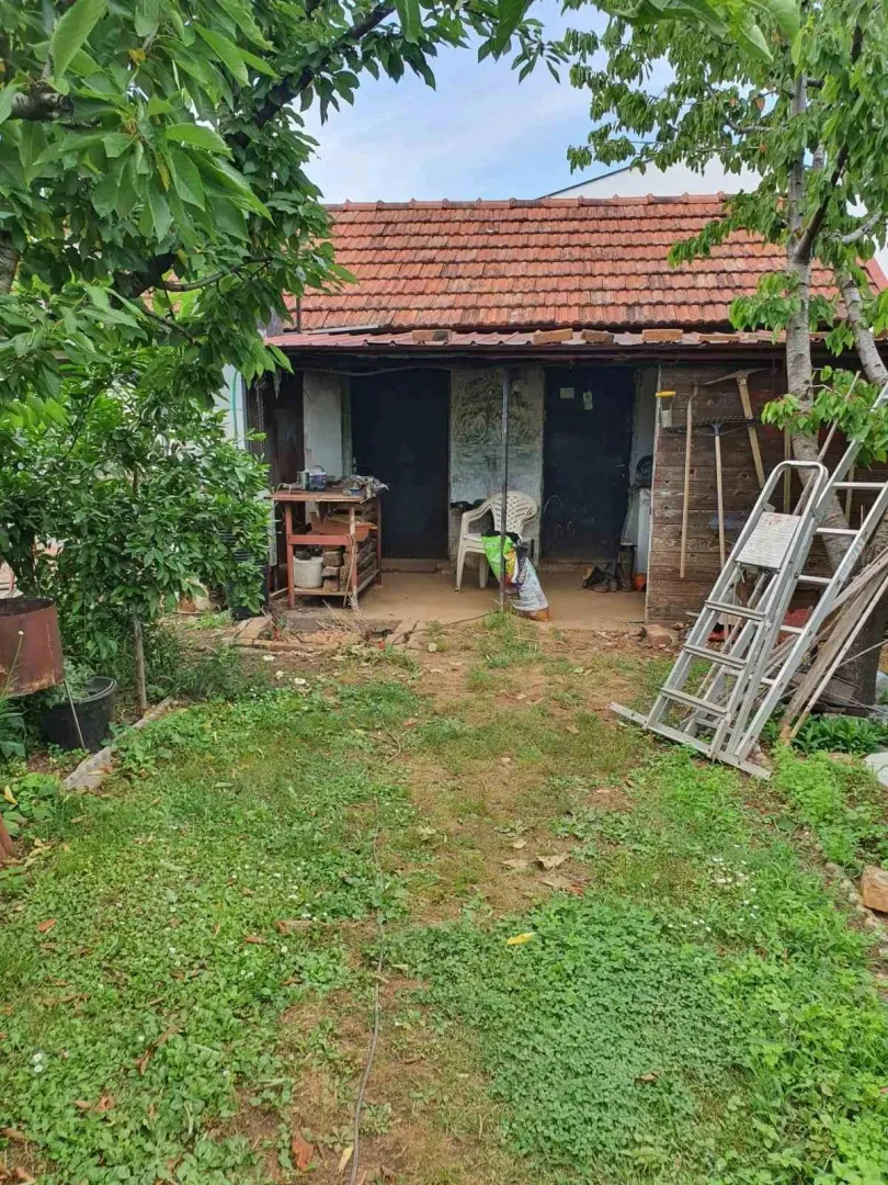 Dvorište sa travnjakom i pomoćnim objektom u pozadini.