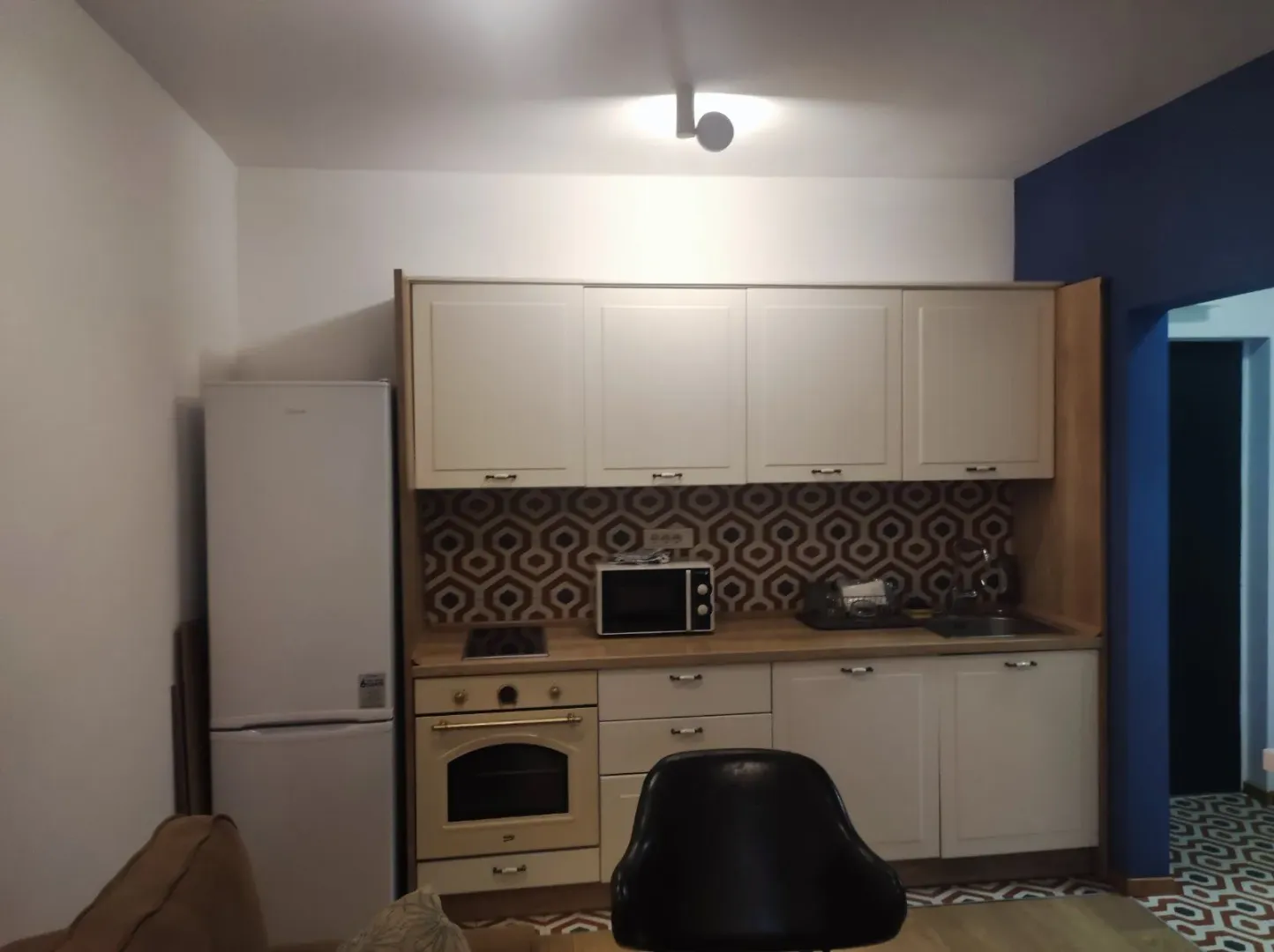 Kitchen equipped with white cabinets, refrigerator, and built-in home appliances.