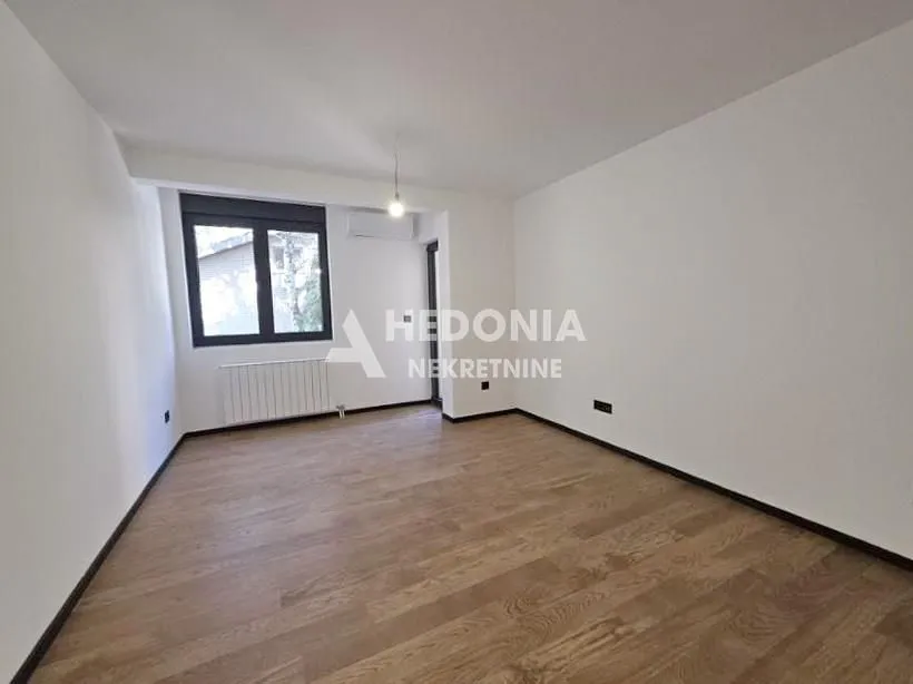 Prazna soba sa drvenim podom i prozorom.