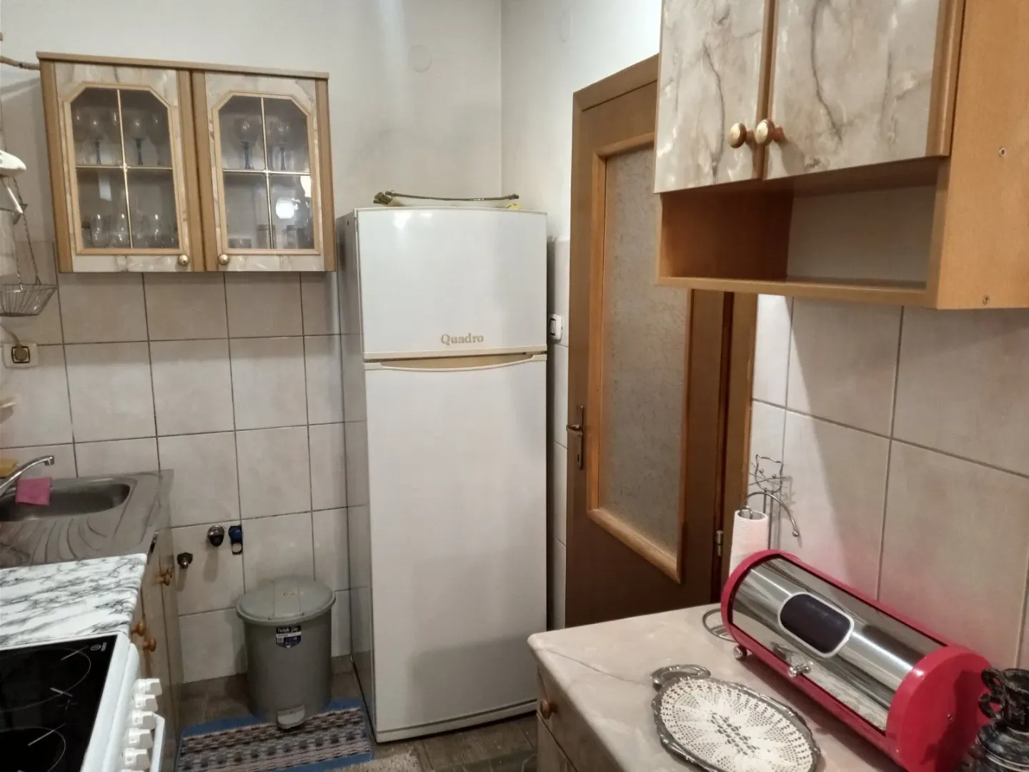 Kuhinja sa frižiderom i visećim elementima.