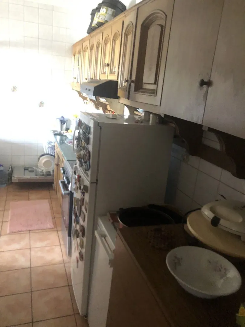 Kuhinja sa drvenim visećim elementima i bijelim frižiderom.
