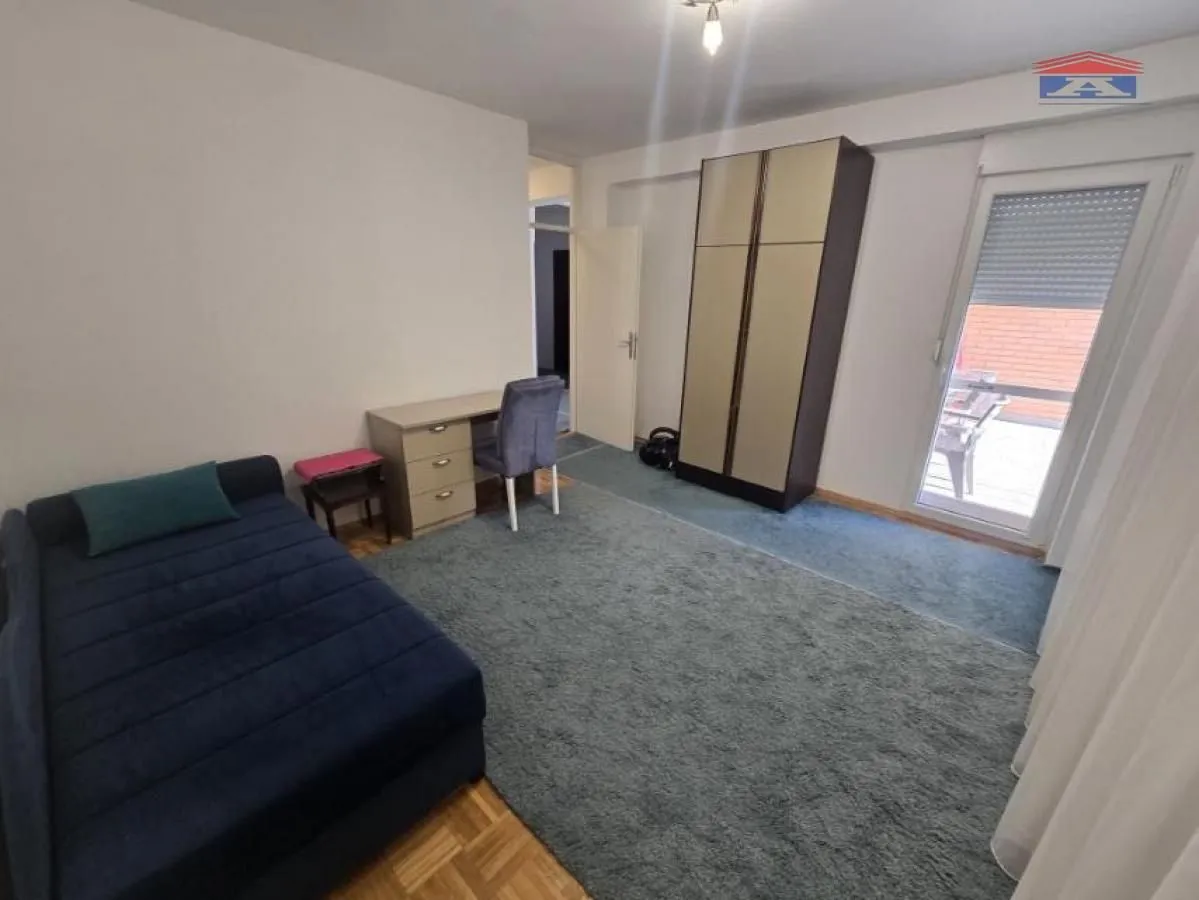 Furnished bedroom with a bed, desk, and wardrobe.
