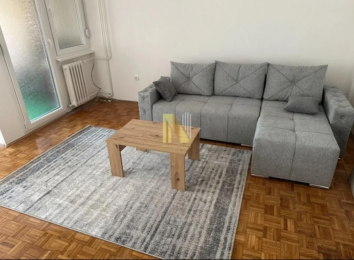 Dnevna soba sa ugaonom garniturom, stočićem i tepihom.