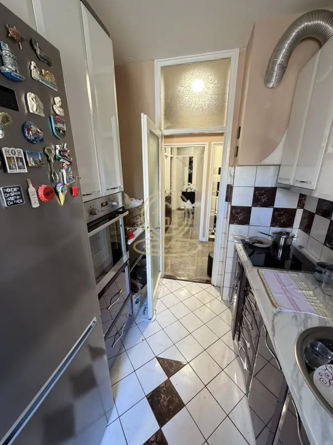 Compact equipped kitchen with white cabinetry and a refrigerator with magnets.