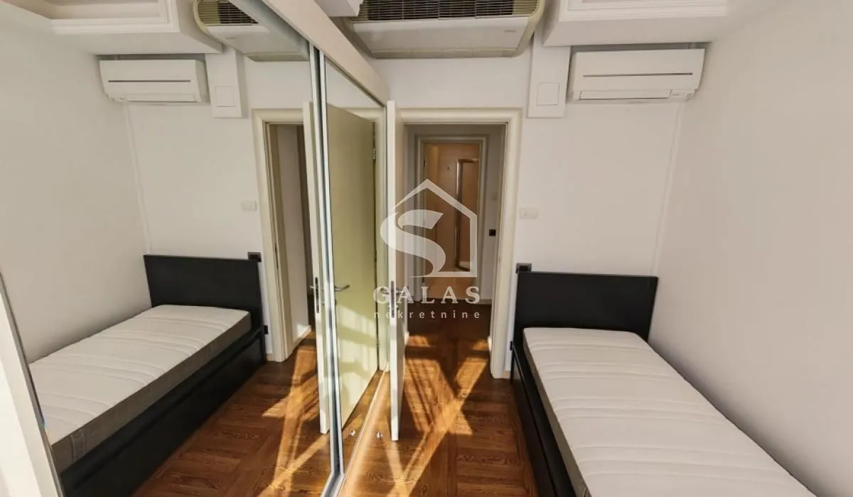 Small bedroom with two single beds and a built-in mirrored wardrobe.