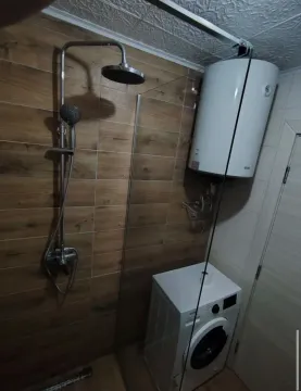Bathroom with a shower cabin, water heater, and washing machine. - image 6