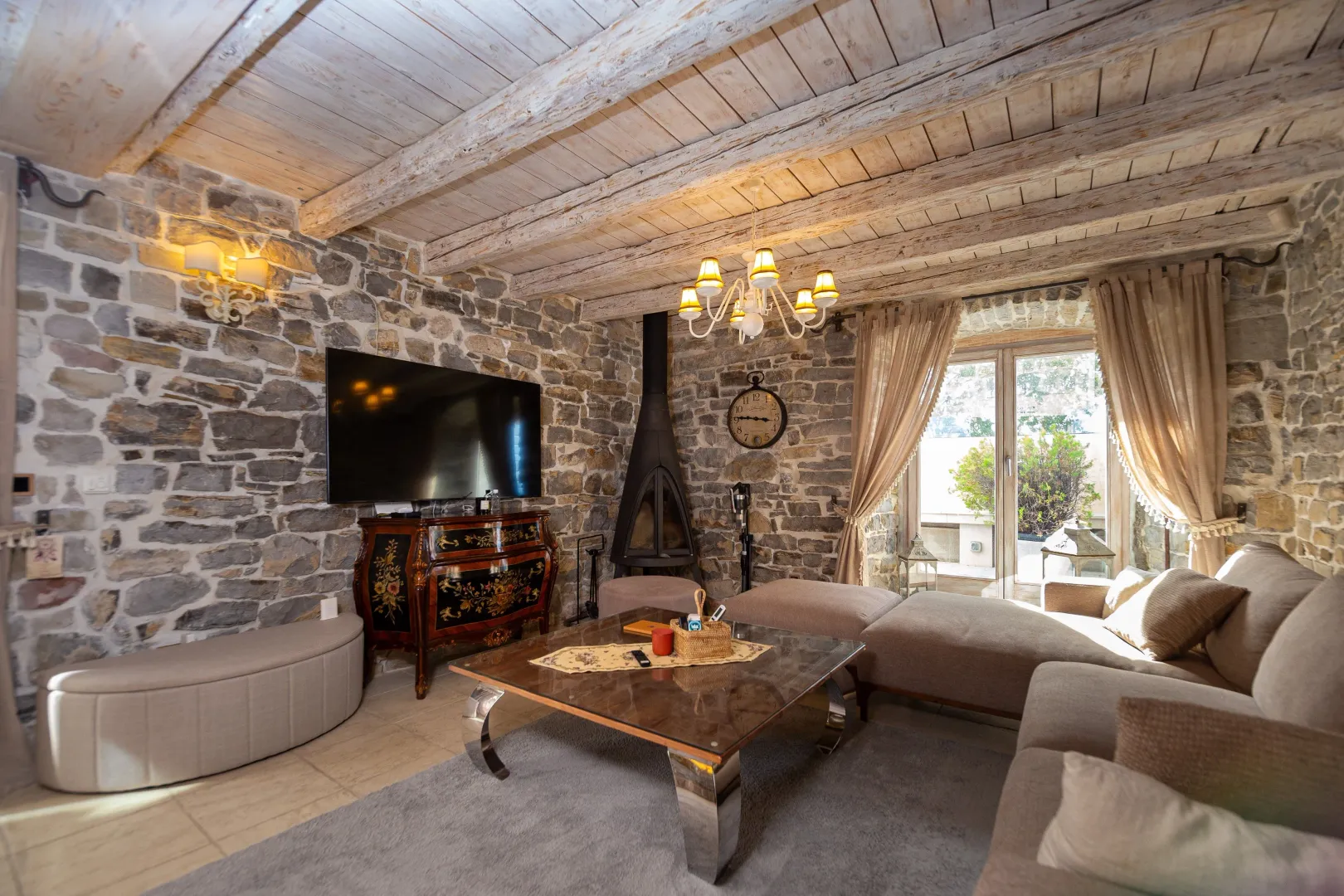 Living room with stone walls, wooden ceiling, and a fireplace.