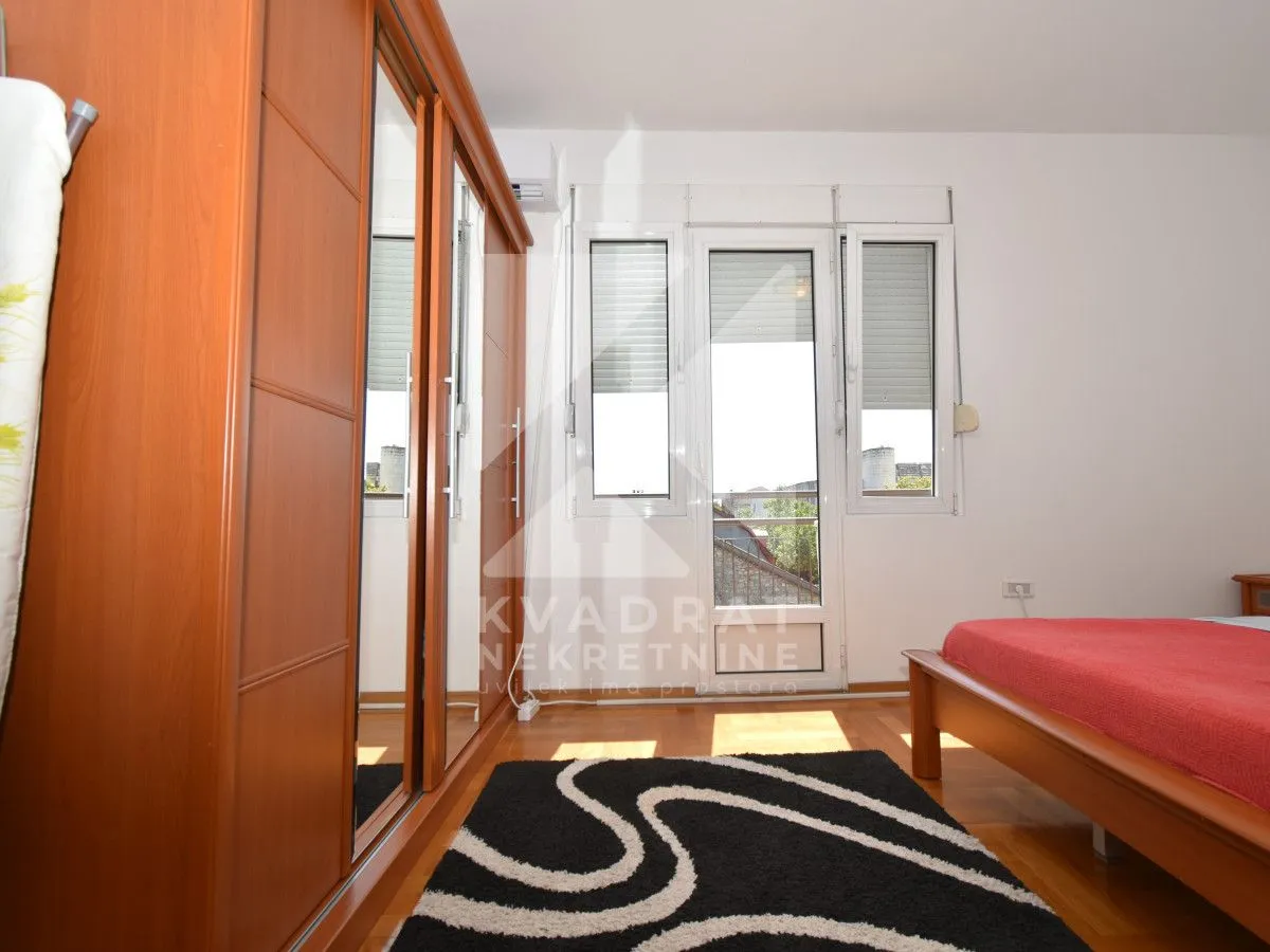 Bedroom with a wooden bed, large mirrored wardrobe, and access to the terrace.