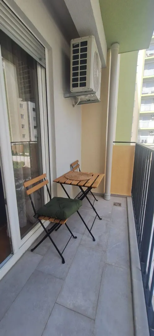 Small furnished balcony space with a wooden table and chairs.