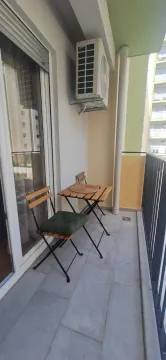 Small furnished balcony space with a wooden table and chairs. - image 7
