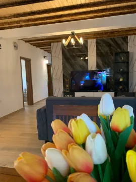 Living room with sofa, television, and wooden beams on the ceiling. - image 6