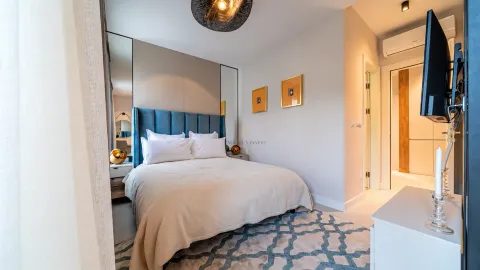 Modern bedroom with a double bed, blue headboard and decorative lighting. - image 17