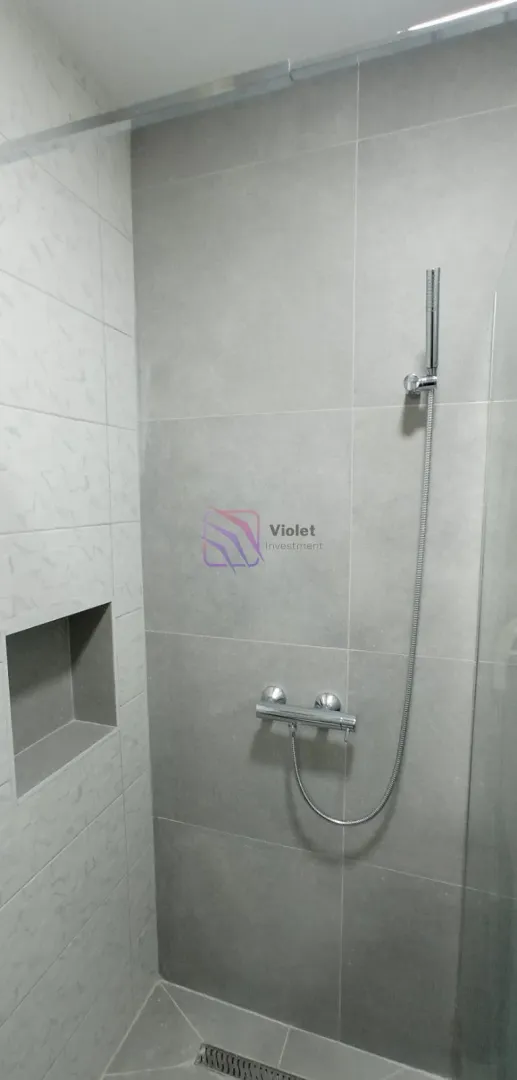 Modern shower enclosure with grey tiles and a built-in niche.