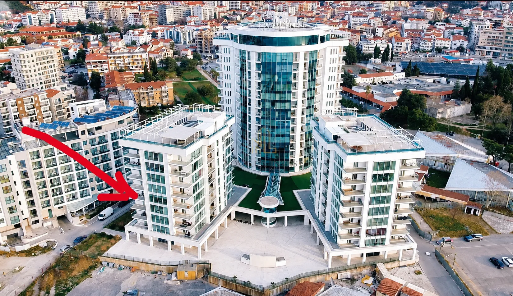 Pogled iz vazduha na kompleks modernih stambenih zgrada sa strelicom koja označava lokaciju.