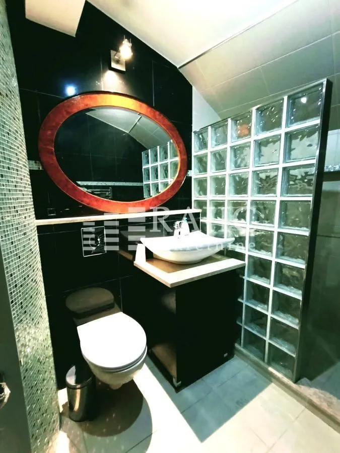 Small bathroom with a washbasin, mirror, and glass block shower cabin.