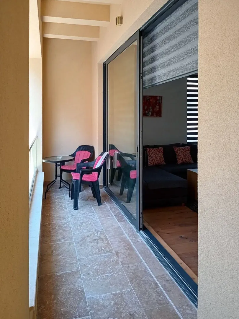 Covered terrace with seating furniture and a view of the interior.