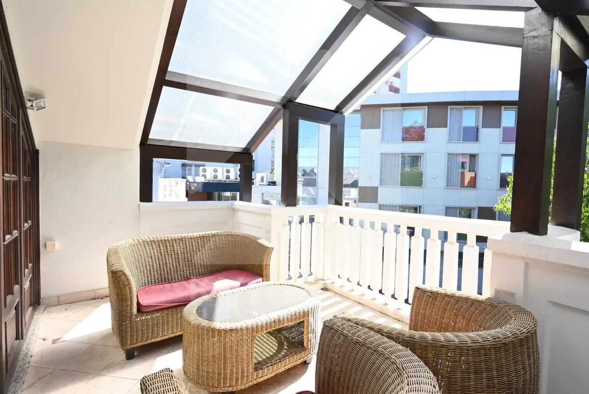 Enclosed terrace with seating furniture and city view.