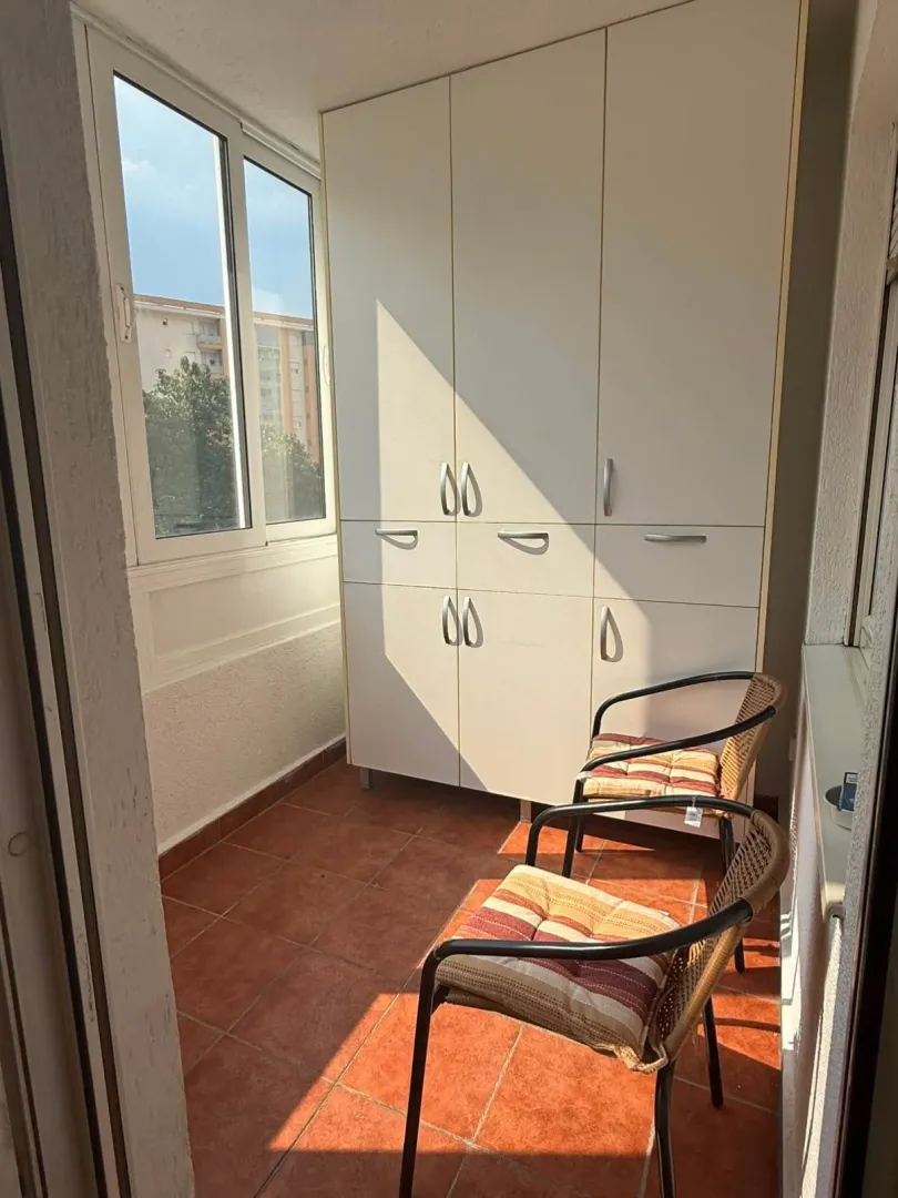 Enclosed balcony with a built-in closet and chairs.