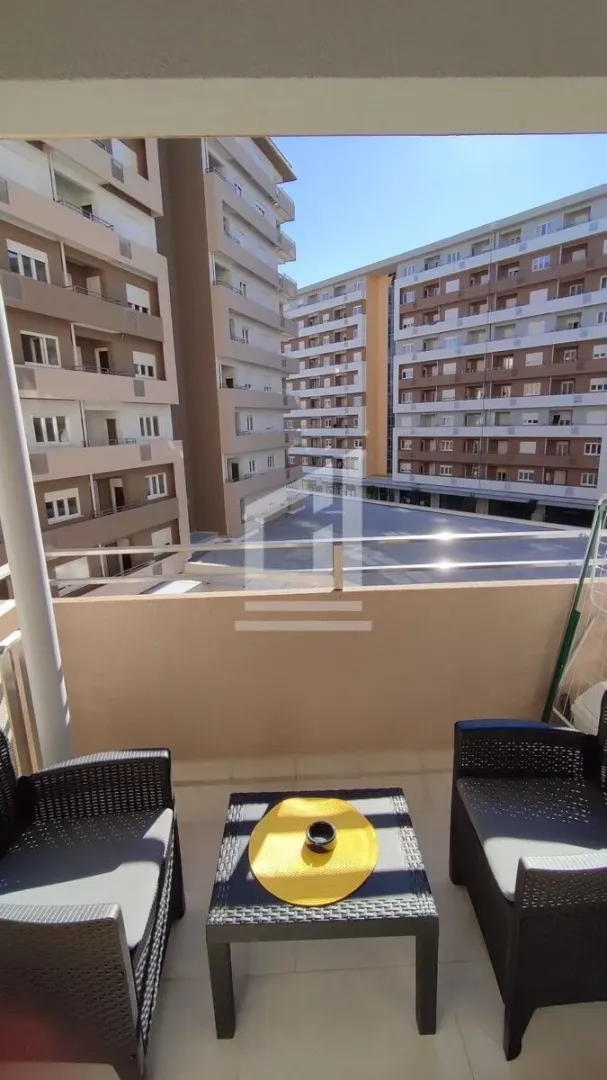 Small furnished balcony with a view of surrounding residential buildings.