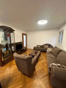 Living room with a sofa, armchair, TV, and display cabinet. - image 17