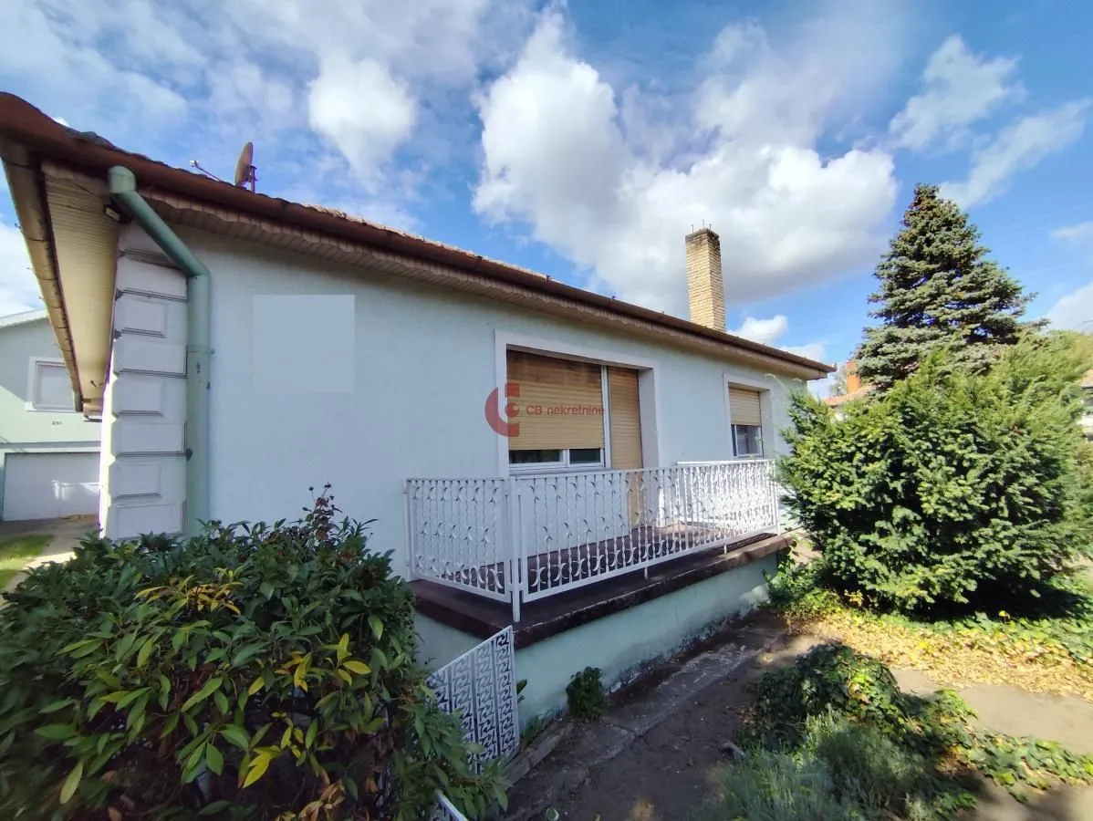 View of the exterior of the house with a balcony and yard.