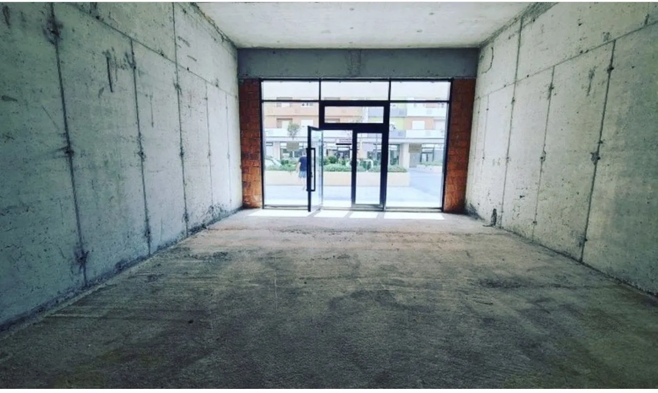 Unfinished commercial space in shell construction phase with glass storefront.