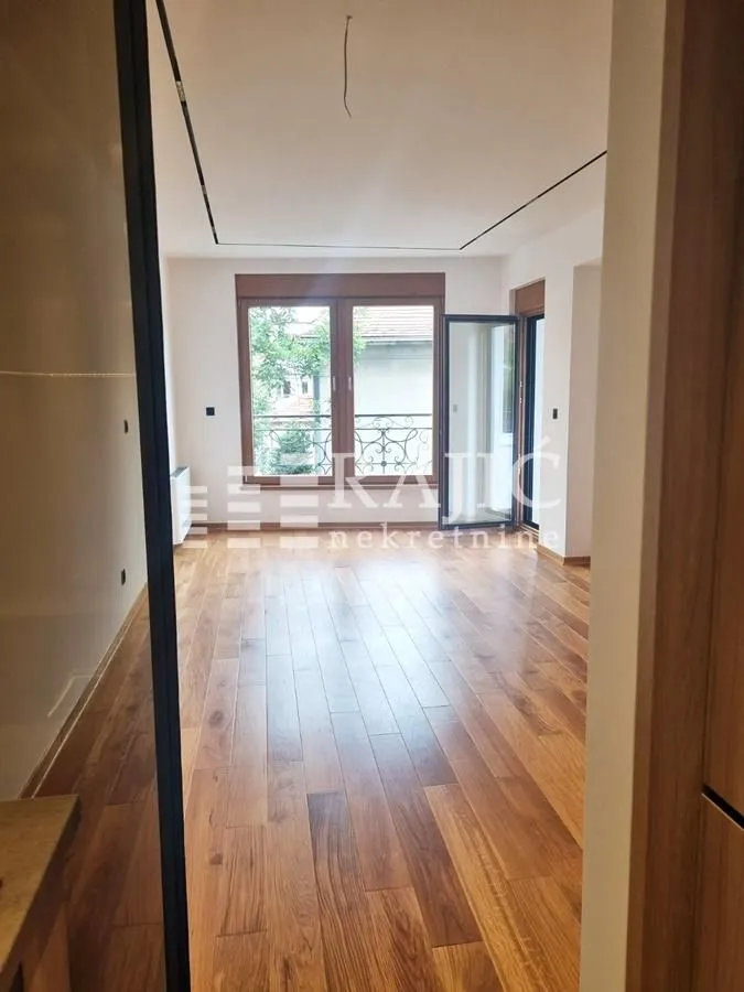 Empty living room with wooden flooring and windows.