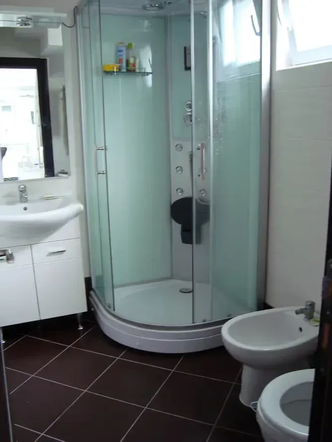 Kupatilo opremljeno tuš kabinom, umivaonikom sa ormarićem, bideom i WC šoljom.