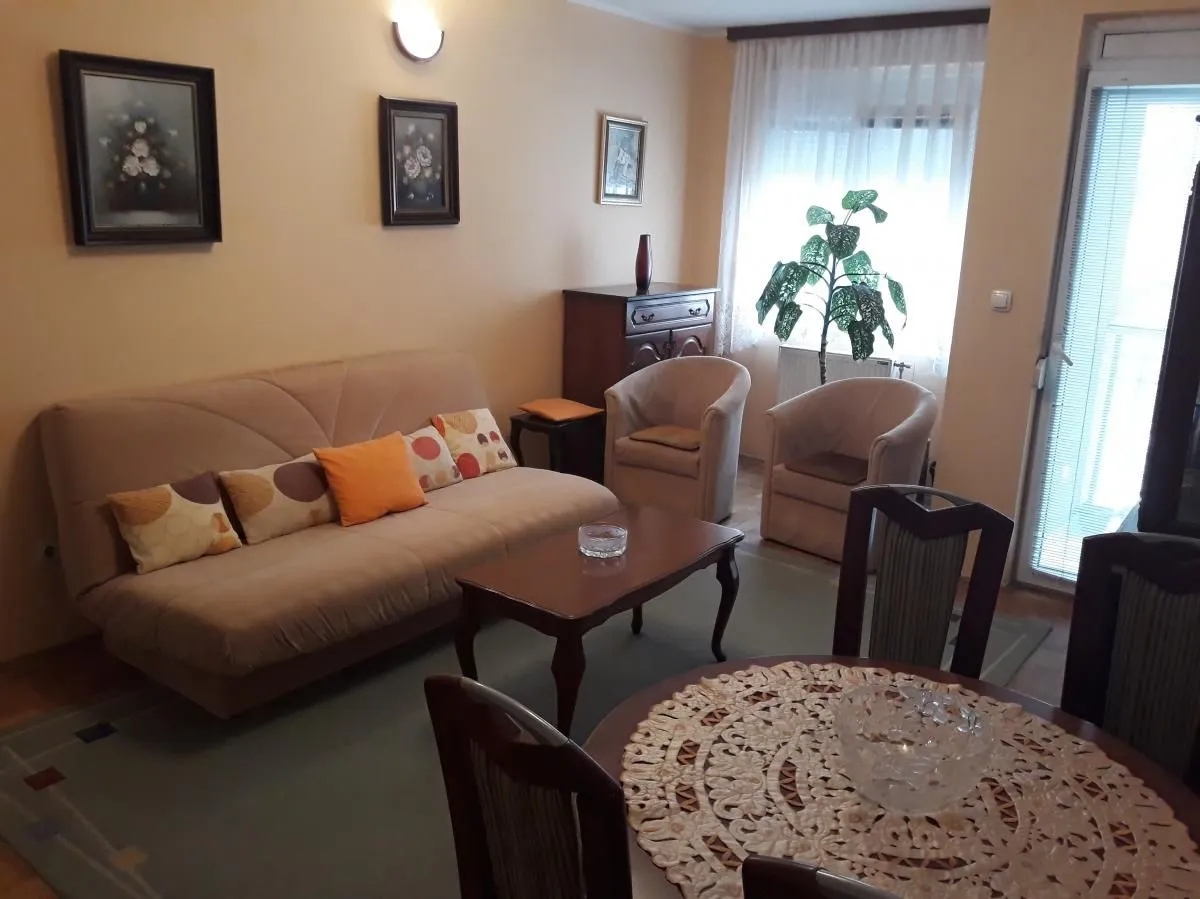 Dnevna soba sa garniturom za sedenje, stočićem i trpezarijskim stolom.