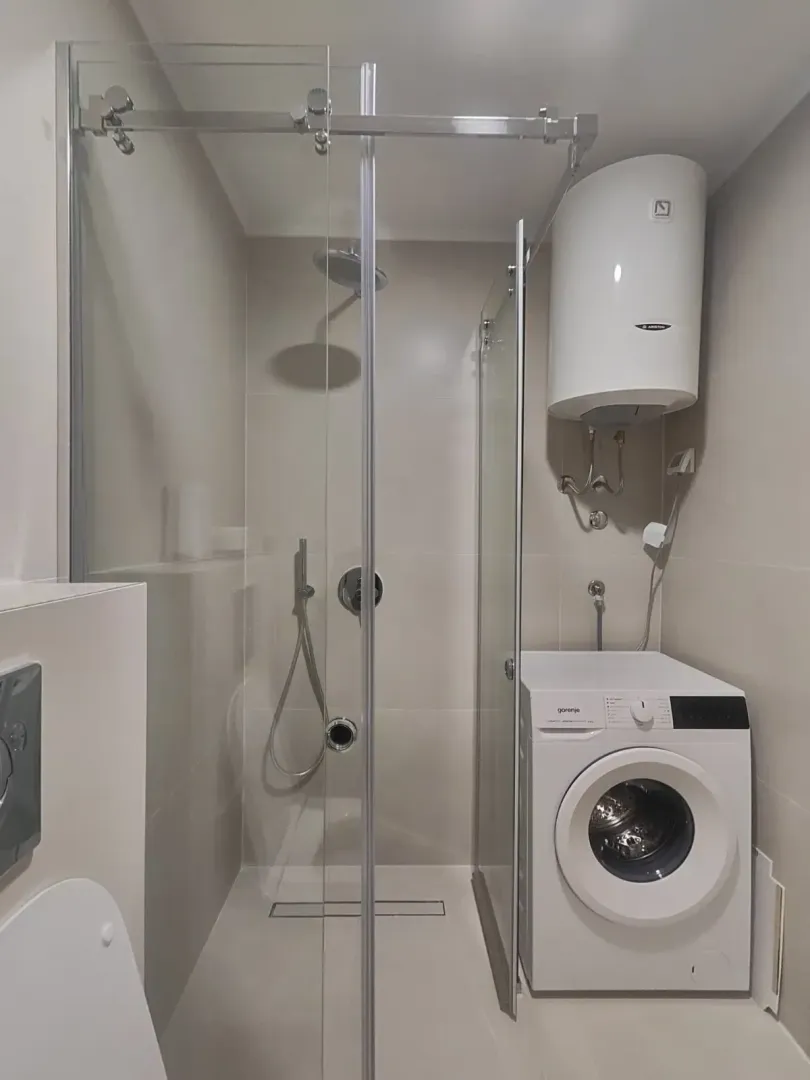 Modern equipped bathroom with a shower cabin and a washing machine.