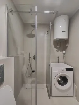 Modern equipped bathroom with a shower cabin and a washing machine. - image 9