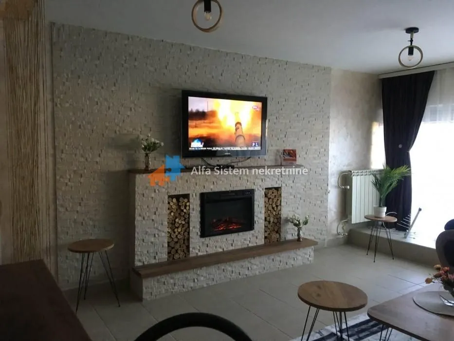 Living room with a decorative stone wall, electric fireplace, and TV.