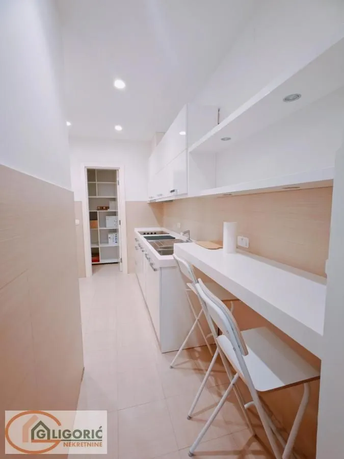 Modern white kitchen with a bar and stools.