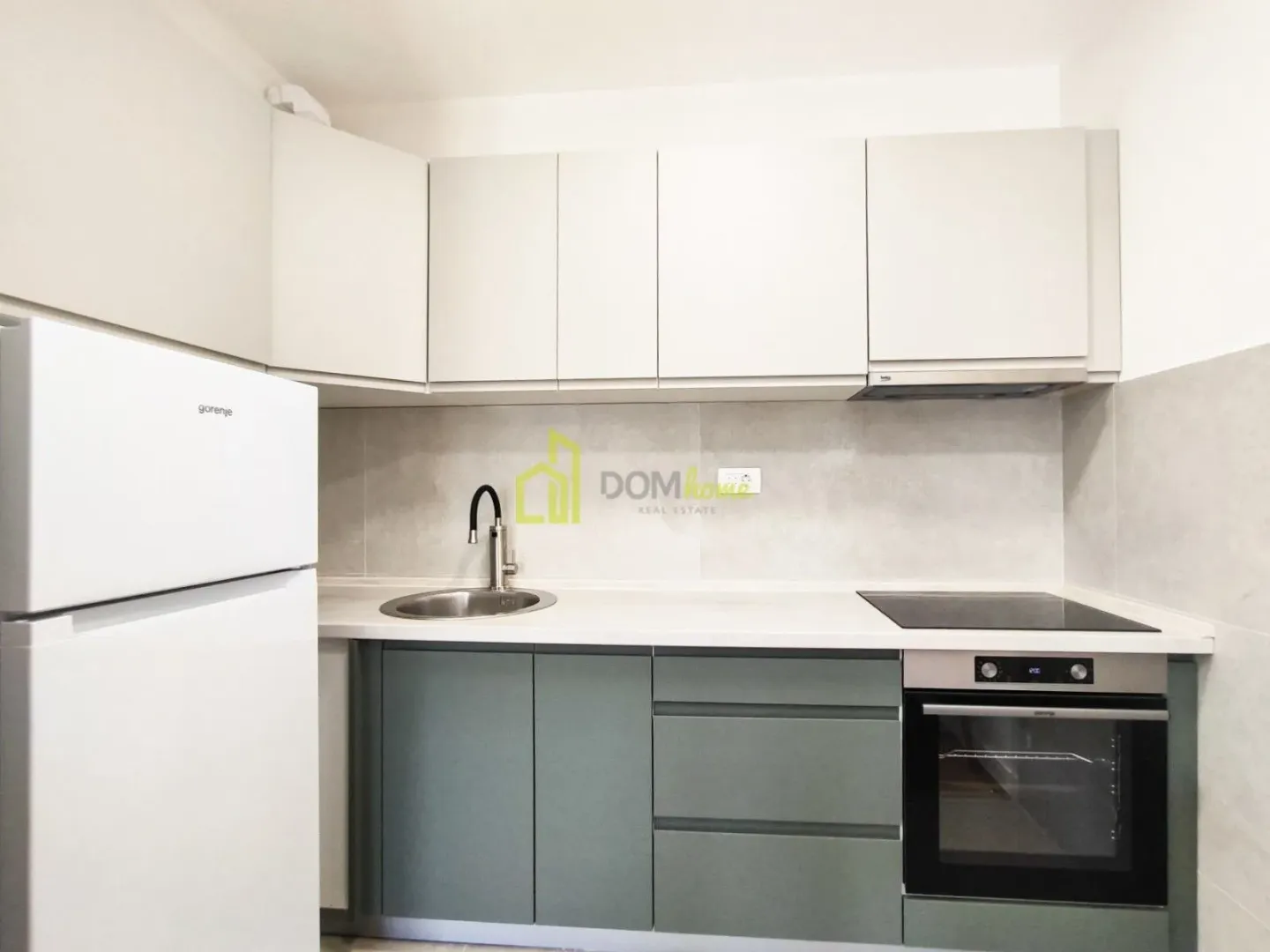 Small kitchen with white wall cabinets, green base cabinets, and built-in appliances.