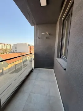 Nenameštena terasa sa staklenom ogradom i pogledom na okolne zgrade i ulicu. - image 12