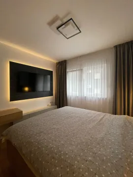 Modern bedroom with a double bed, wall-mounted TV, and a window with curtains. - image 2