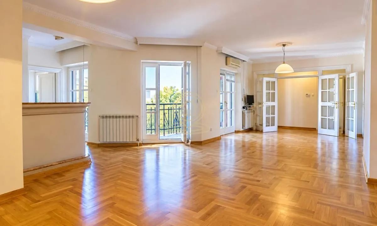 Spacious empty living room with parquet flooring and access to a balcony.