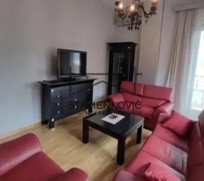 Dnevna soba sa crvenim garniturama za sedenje, TV komodom i lusterom. - image 4