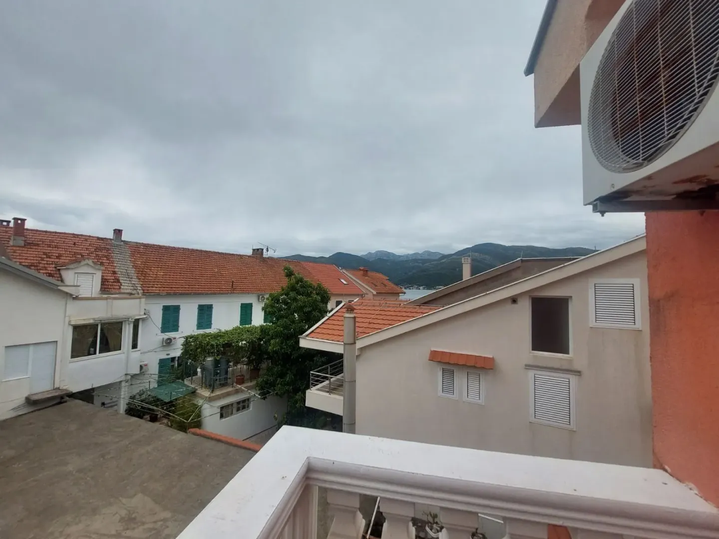 Pogled sa balkona na okolne kuće i planine.