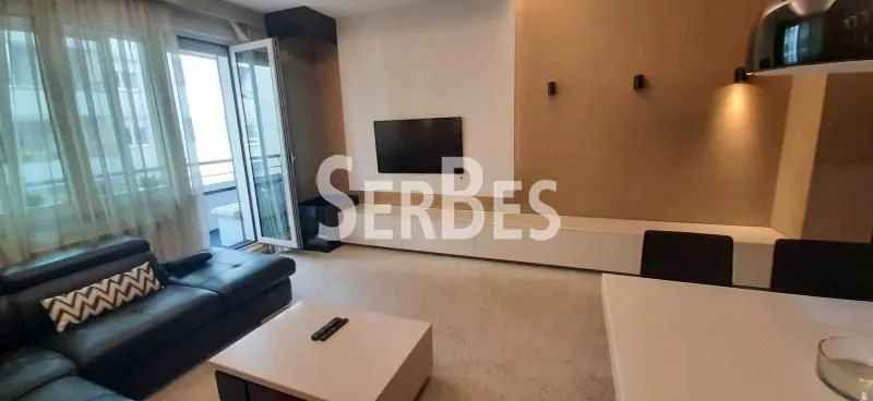 Dnevna soba sa garniturom, televizorom i trpezarijskim stolom.