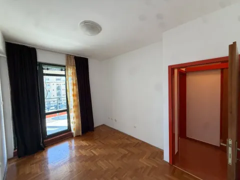 Empty room with parquet flooring, a large window, and a doorway leading to the hallway. - image 6
