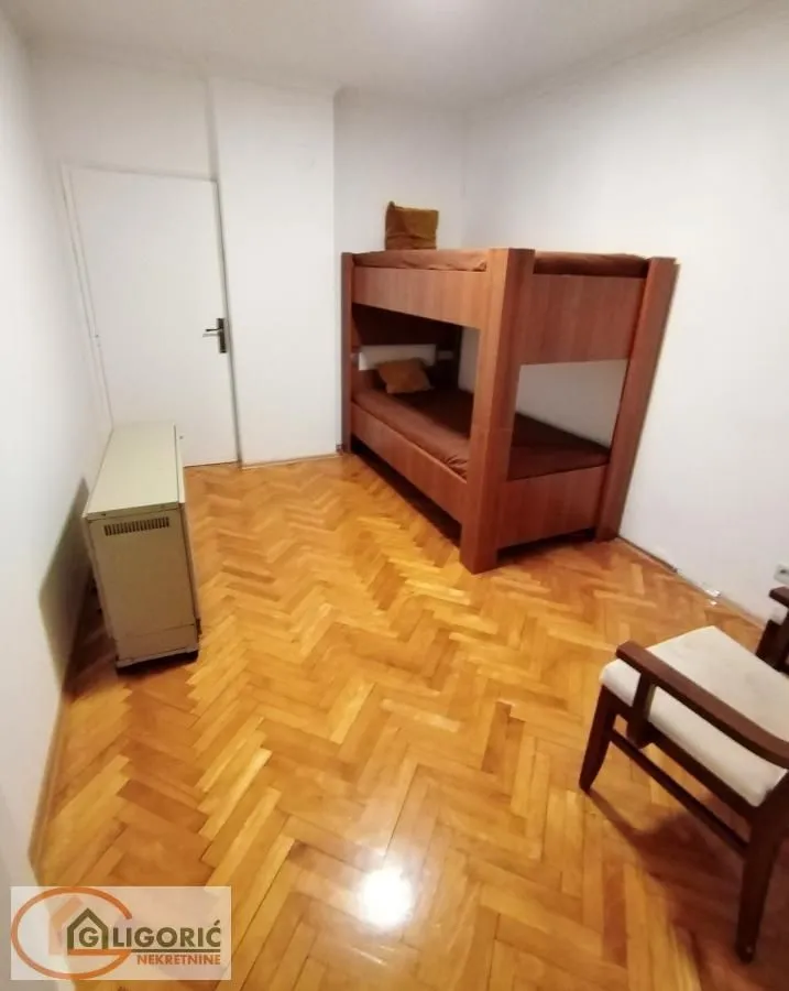 Small bedroom with a bunk bed and hardwood flooring.