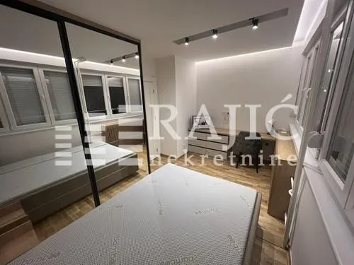 Modern bedroom with a bed, large wardrobe, and desk.