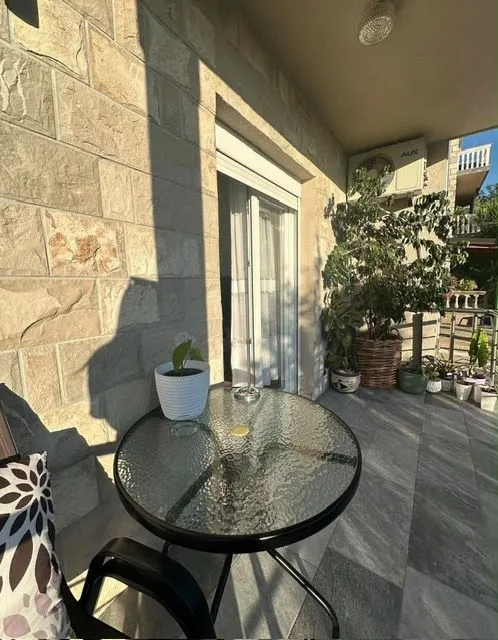 Namještena terasa sa stolom, stolicama i ukrasnim biljkama.