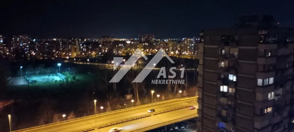 Noćni pogled sa prozora na osvetljeni grad i ulicu.