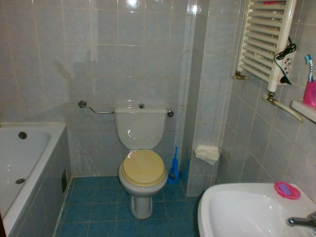 Kupatilo opremljeno sanitarijama, kadom i pločicama na zidovima i podu.