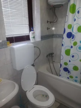 A simple bathroom with a bathtub, toilet, and a window. - image 7