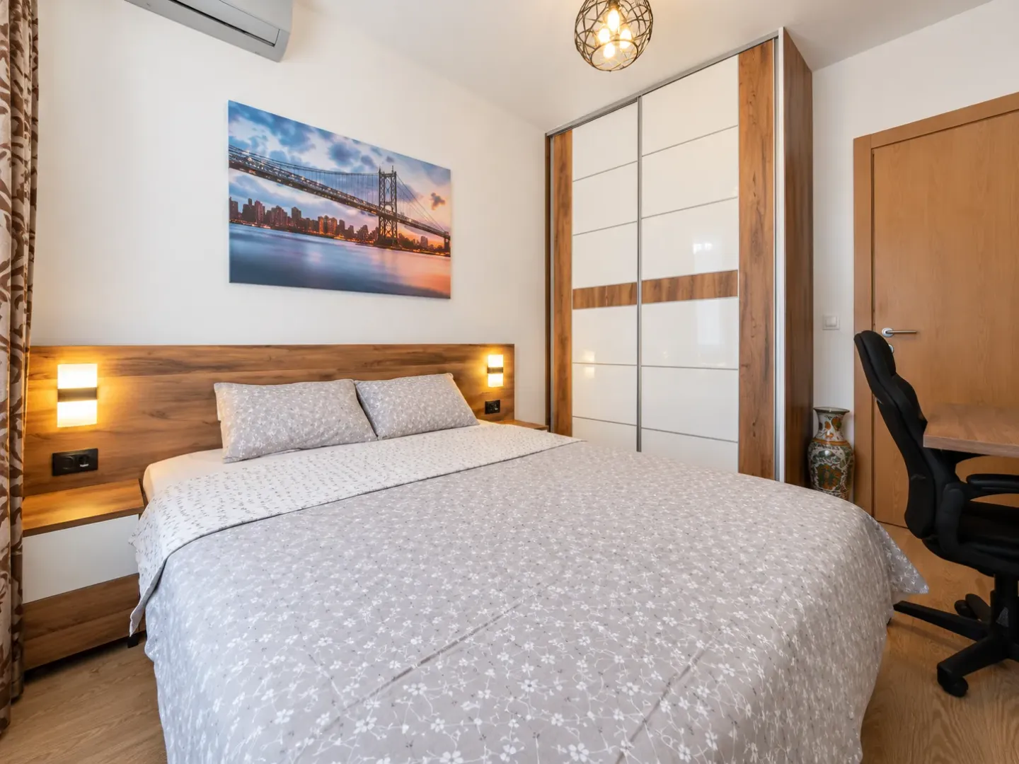 Furnished bedroom with a double bed, large wardrobe, and a desk.