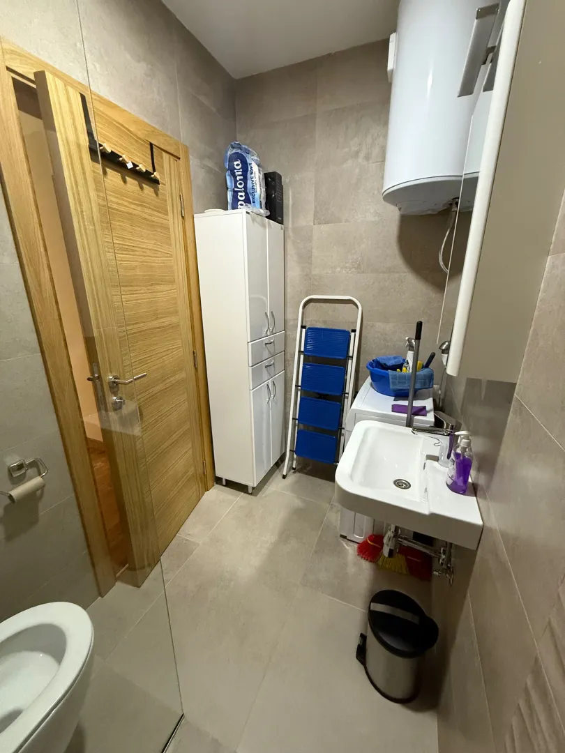 Small bathroom with a sink, washing machine, cabinet, and toilet.