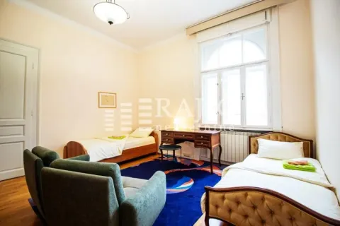 Spacious bedroom with two single beds, a desk, and a large window. - image 9